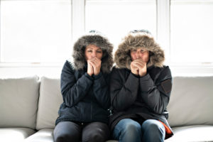 Couple in winter jackets due to a cold spot in their house