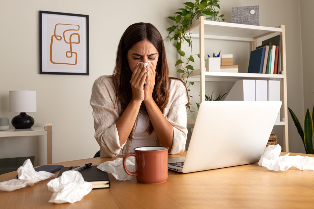 woman blowing nose from allergies